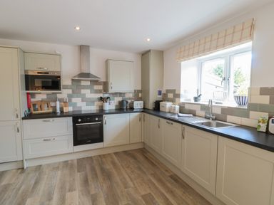 A kitchen with cabinets oven microwave sink and window at Eider Cottage in Warkworth