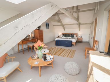 A bedroom with a bed cushions lamps wooden furniture and a coffee table with cups at Eider Cottage in Warkworth
