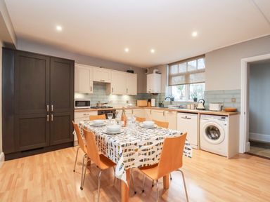 A kitchen with a wooden dining table set for six and cabinets at 11 The Craighurst in Southwold
