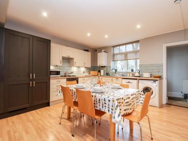 A kitchen with a dining table set with dishes and glassware and wooden chairs at 11 The Craighurst in Southwold
