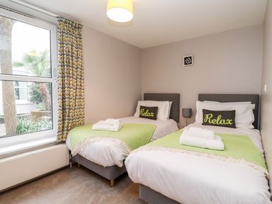 A bedroom with two single beds each with green throws and relax pillows at 11 The Craighurst in Southwold