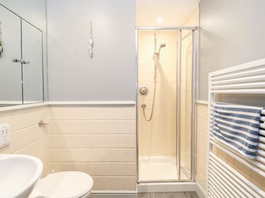 A bathroom with a shower enclosure toilet sink and a towel radiator with a striped towel at 11 The Craighurst in Southwold