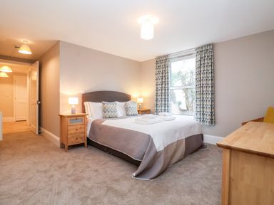 A bedroom with a double bed bedside tables lamps a window with curtains and a wooden desk at 11 The Craighurst in Southwold