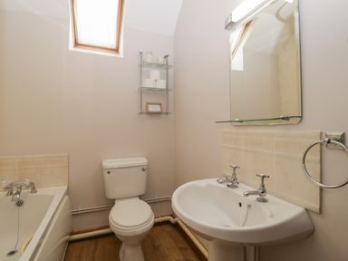 A bathroom with a bathtub toilet sink and a mirror at Anvil Cottage in Gatcombe near Blakeney