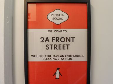 A framed Penguin Books style welcome sign for 2a Front Street hanging on a wall at 2A Front Street Embleton
