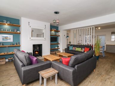 A living room with gray sofas wooden tables fireplace and shelving at 2A Front Street in Embleton