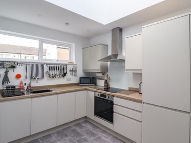 A kitchen with white cabinets a wooden countertop a stainless steel oven and hood a sink and a window at 2A Front Street in Embleton