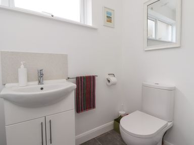 A bathroom with a white sink cabinet a mirror a toilet and a striped towel at 2A Front Street Embleton