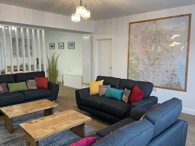 A sitting room with black sofas and wooden coffee tables with a large map on the wall at 2A Front Street in Embleton