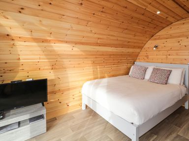 A bedroom with a bed pillows and a television on a stand at The Wheelhouse Pod No 2 in Burtonport County Donegal