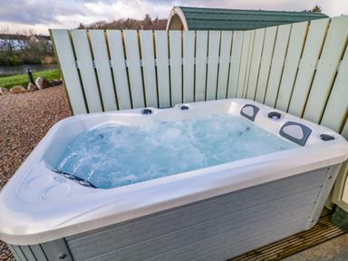An outdoor hot tub with bubbling water next to a light green wooden fence at The Wheelhouse Pod No 2 in Burtonport County Donegal