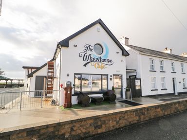 The exterior of The Wheelhouse Cafe with a white facade and seating made from barrels at The Wheelhouse Pod No 2 Burtonport County Donegal