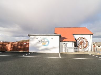 Exterior of a building with a red roof a water wheel and a sign saying The Wheelhouse Cafe at The Wheelhouse Pod No 3 Burtonport County Donegal