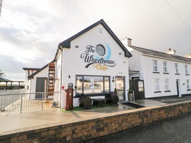 The exterior of The Wheelhouse Cafe with a white facade wooden furniture and an old gas pump at The Wheelhouse Pod No 3 Burtonport County Donegal