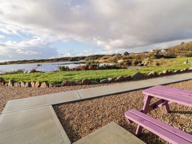 A picnic table near a pond with rocks and grass at The Wheelhouse Pod No 9 in Burtonport County Donegal