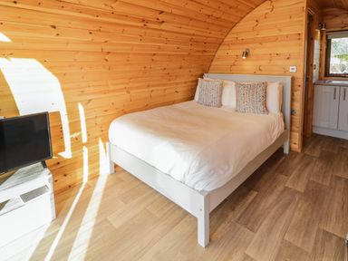 A bedroom with a double bed with pillows and a television on a stand at The Wheelhouse Pod No 9 in Burtonport County Donegal