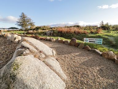 A gravel pathway bordered by rocks with a sign pointing to the Wheelhouse Cafe in a grassy outdoor area at The Wheelhouse Pod No 9 Burtonport County Donegal