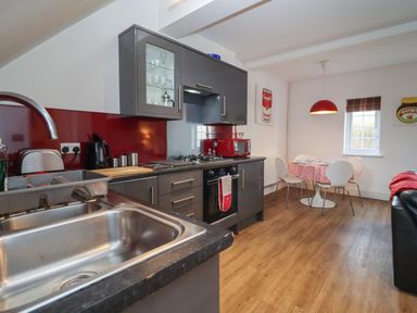 A kitchen with a sink stove and dining table with chairs at The Little White Cottage in Milton-Under-Wychwood