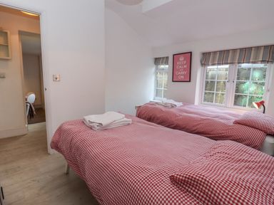 A bedroom with two single beds with red checkered bedding and a keep calm poster at The Little White Cottage in Milton-Under-Wychwood