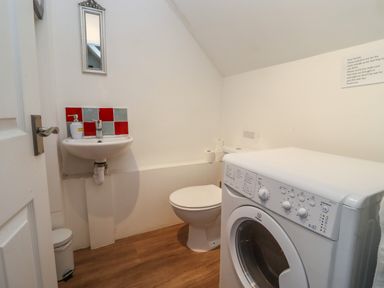 A bathroom with a washing machine sink toilet and mirror at The Little White Cottage in Milton-Under-Wychwood