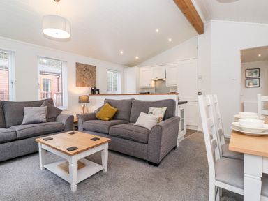A living room with two grey sofas a wooden coffee table and a dining table with chairs at Bowness Bay Lodge Oakside 16 Fallbarrow Park near Bowness-On-Windermere