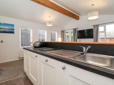 A kitchen area with a sink and countertop and windows with blinds at Bowness Bay Lodge Oakside 16 Fallbarrow Park near Bowness-On-Windermere