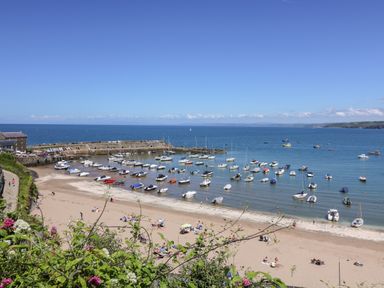 A beach with boats anchored in the water and people on the sand at Valley View Hideaway in Ffostrasol