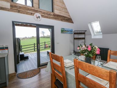 A dining room with a table set for meals at Valley View Hideaway in Ffostrasol