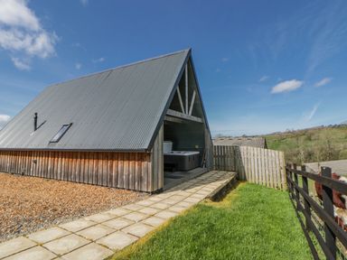 A modern building with a pathway and grass at Valley View Hideaway Ffostrasol