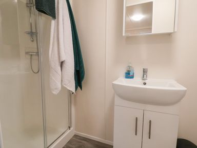 A bathroom with a shower cubicle with towels hanging and a basin with a mirror cabinet at Holmside in Audley Brow near Market Drayton