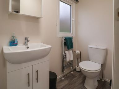 A bathroom with a sink cabinet toilet window and towel rack at Holmside Audley Brow near Market Drayton