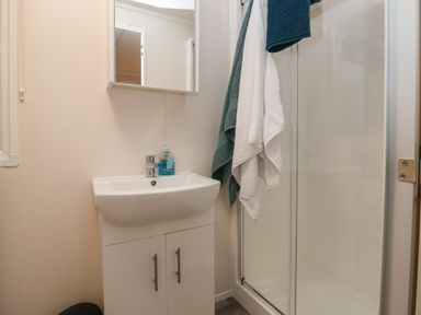 A bathroom with a sink cabinet mirror shower cubicle and towels hanging at Holmside in Audley Brow near Market Drayton
