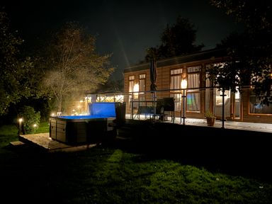 A wooden deck with a hot tub and outdoor furniture next to a house at Holmside Audley Brow near Market Drayton
