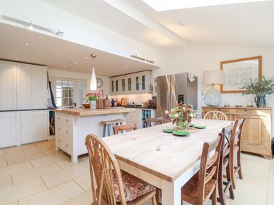 A kitchen and dining area with wooden table and chairs a kitchen island and stainless steel refrigerator at Beta Cottage in Walberswick