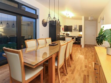 A kitchen and dining area with a wooden table and chairs next to large windows and black cabinets at 2 Strathtay Lodges in Aberfeldy