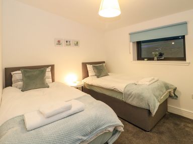 A bedroom with two single beds side by side with pillows and folded towels on the beds at 2 Strathtay Lodges in Aberfeldy