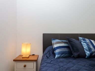 A bed with blue pillows and a bedside table with a lamp in a bedroom at South Holm in Moreleigh