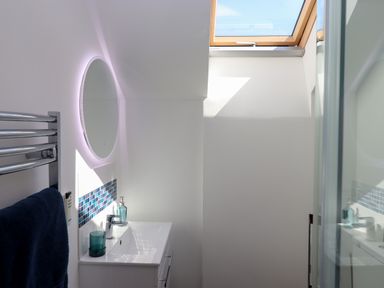 A bathroom with a sink vanity a round mirror a towel on a metal rack and a skylight window at South Holm in Moreleigh