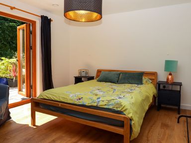 A bedroom with a wooden bed and green bedding next to black bedside tables with a radio and a lamp at South Holm in Moreleigh
