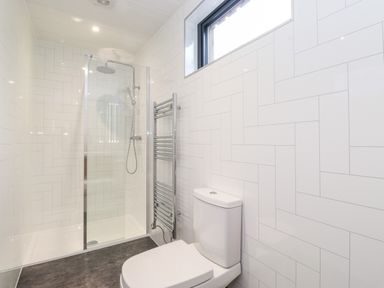 A bathroom with a walk-in shower a towel radiator and a toilet at The Gardener's Retreat in Hutton John near Penruddock