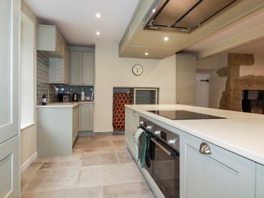 A kitchen with cabinets an oven a stovetop a sink a toaster and a wine rack at Tretoil Farm House Bodmin