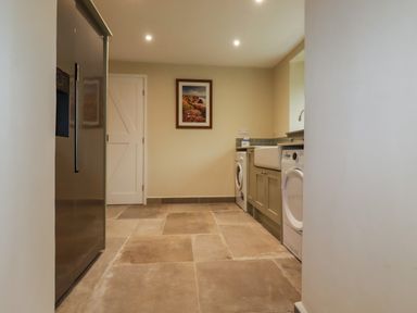 A laundry room with a washing machine, dryer, sink, refrigerator, and a framed picture on the wall at Tretoil Farm House in Bodmin