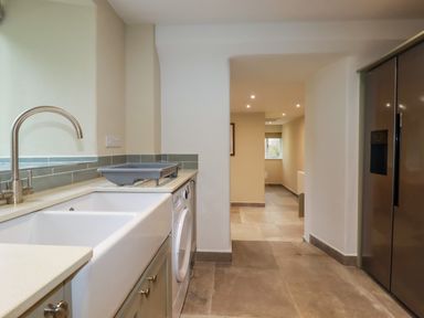 A laundry room with a sink washing machine and refrigerator at Tretoil Farm House in Bodmin