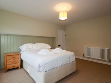 A bedroom with a bed towels bedside table radiator and light fixture at Tretoil Farm House in Bodmin