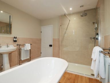 A bathroom with a bathtub sink shower and towel racks at Tretoil Farm House in Bodmin