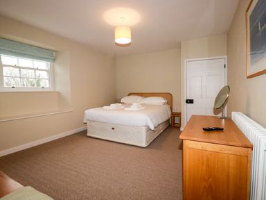 A bedroom with a bed towels on it a wooden dresser and a window at Tretoil Farm House in Bodmin