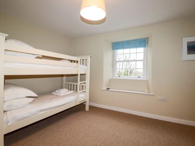 A bedroom with a bunk bed and a window with a blue blind at Tretoil Farm House in Bodmin