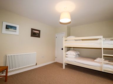A bedroom with bunk beds radiator framed pictures and a pendant light at Tretoil Farm House Bodmin
