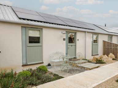 An outdoor area with a door, windows, table, and chairs at The Little Loft in Burford