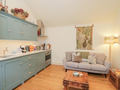 A kitchen with blue cabinets and a sofa at The Little Loft in Burford